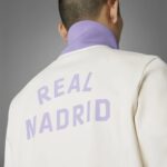 Back of a person in a white jacket with a lavender shirt; large purple 'REAL MADRID' text visible on the back.