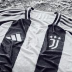 Close-up of a black-and-white Juventus football jersey fabric showing part of the crest and raised stars, with textured material