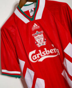 Red Liverpool FC jersey hanging on a hanger, featuring Adidas logo, crest, and Carlsberg sponsor.