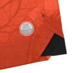 Close-up of orange fabric with a circular reflective patch and black interior lining.