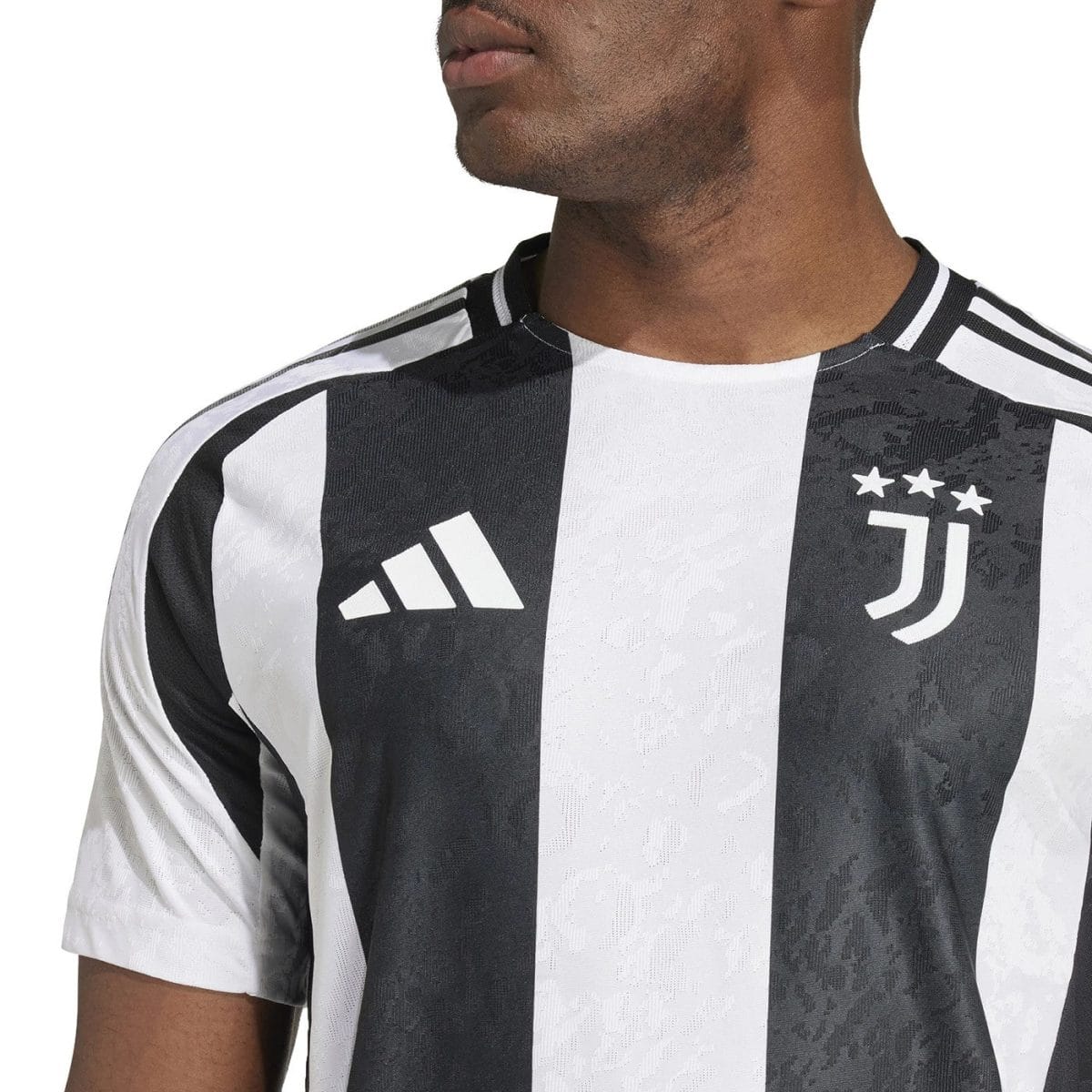 Close-up of a person wearing a black-and-white Juventus jersey with the Adidas logo and the club crest with stars on the chest.