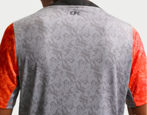 Back view of a gray camouflage-patterned sports jersey with orange sleeves and a small black 'CFC' logo at the neckline area.