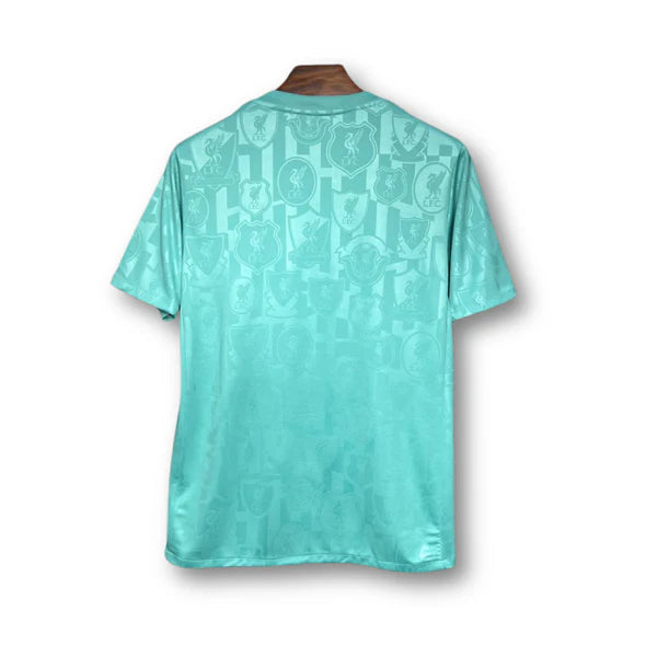 Turquoise short-sleeve soccer jersey, back view, with a subtle repeating crest pattern fading toward the hem.
