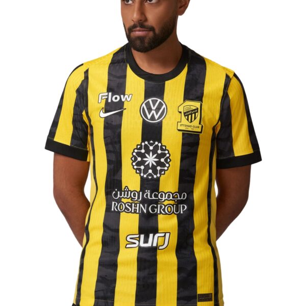 Man wearing a yellow and black striped soccer jersey with logos and crest visible on the chest.