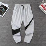 Gray Nike jogger pants with black panel accents, laid flat on a dark wood floor.