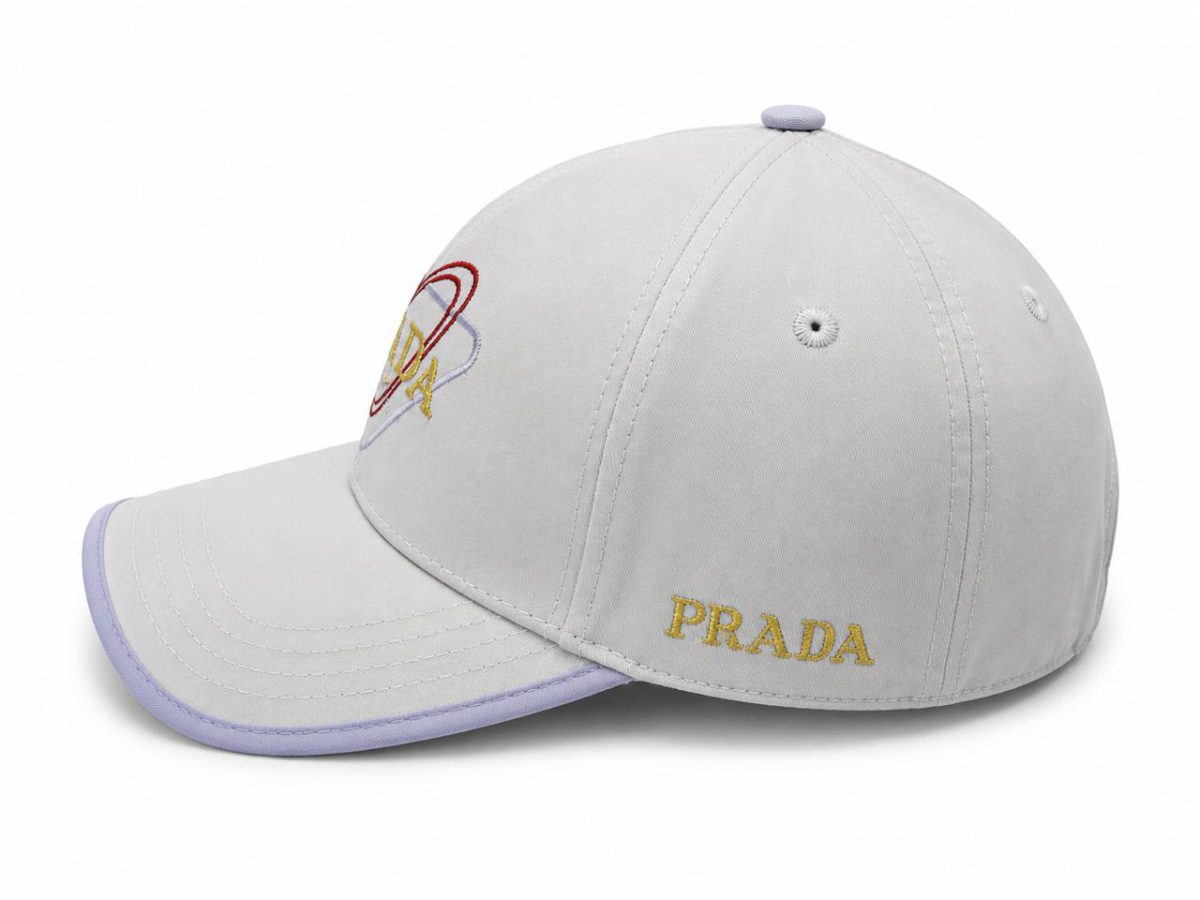 Light gray Prada baseball cap with a lavender brim and gold 'PRADA' embroidery on the front.
