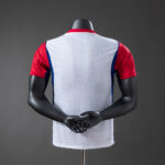 2d1443bf | UAE SPORT STORE Back view of a white athletic jersey worn over red sleeves on a black mannequin.
