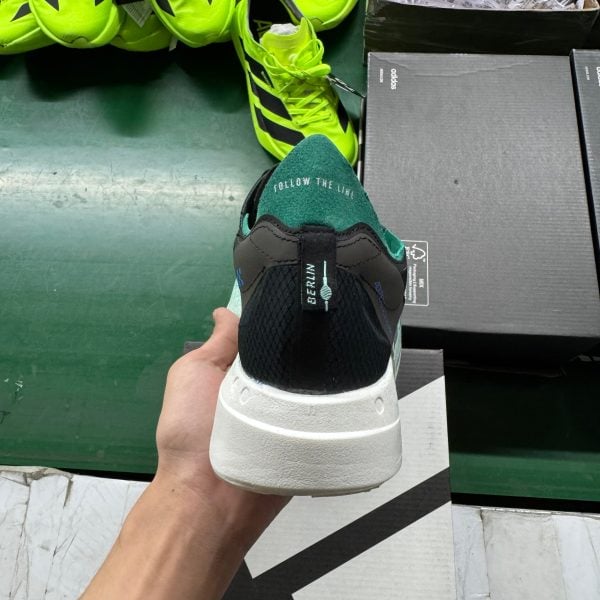 Person holds a bright neon yellow athletic shoe in a store, with additional neon shoes and shoe boxes in the background.