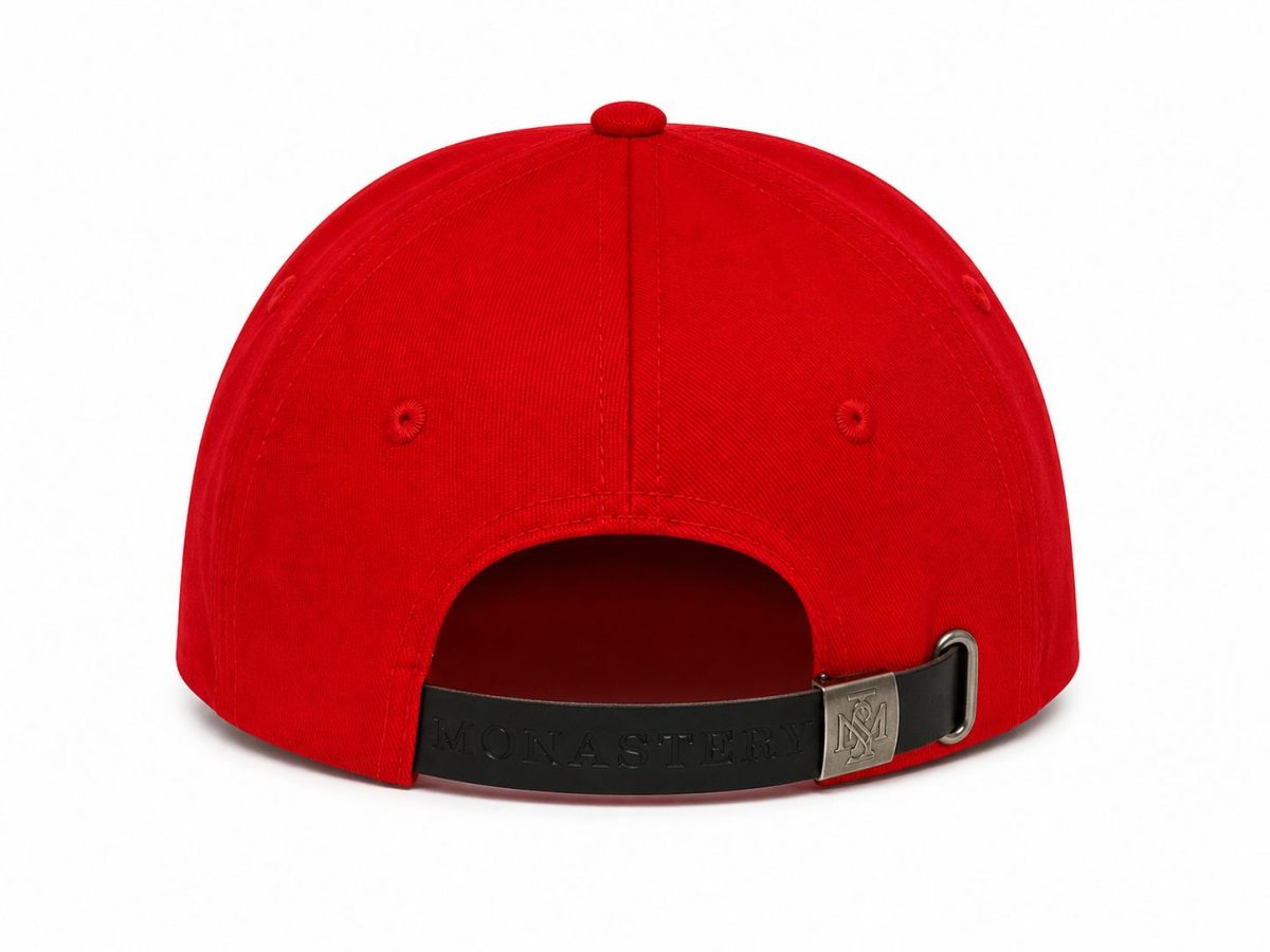 Back view of a red baseball cap with an adjustable black strap and metal buckle (MONASTERY branding).