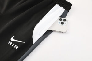 Black Nike Air track pants with a white stripe and a smartphone tucked into the side pocket