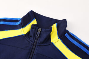 2e536482 | UAE SPORT STORE Close-up of a navy sport jacket collar with blue and yellow piping and a front zipper.