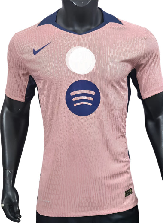 Front view of a pink athletic jersey on a mannequin, featuring a white circle logo above a blue Spotify logo and a blue Nike swoosh on the chest.