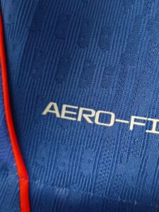 Close-up of blue fabric with the text 'AERO-FI' and a red zipper edge on the left side.