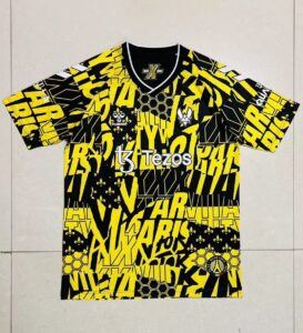 Vibrant black-and-yellow graphic sports jersey laid flat, featuring sponsor text and team logos across the front and sleeves