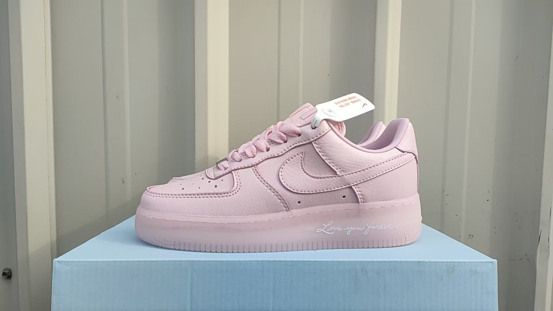 306479e8 | UAE SPORT STORE Pink Nike sneaker on a light blue box, side view showing the swoosh detail