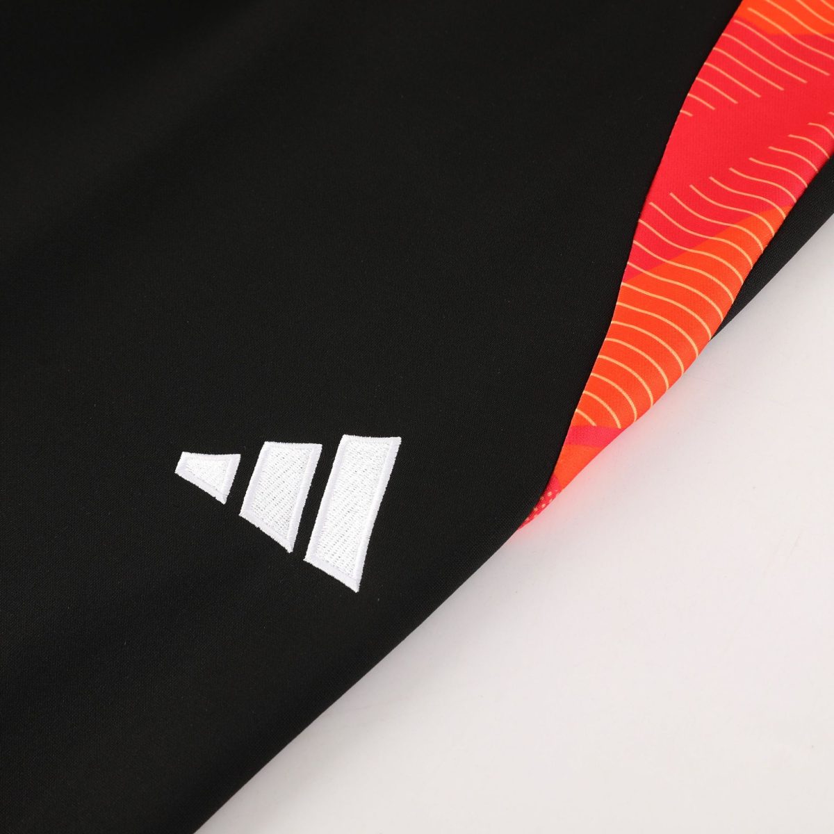 Close-up of black fabric with white stitched rectangular patches and an orange patterned trim along the edge.