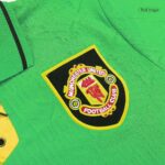 Close-up of a Manchester United Football Club crest patch on a bright green jersey with a yellow border.