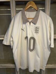 White England football jersey on a hanger, with gray collar, Puma logo and 10 on the front, and the three lions crest on the chest.