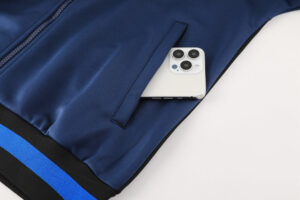 31fbc755 | UAE SPORT STORE White iPhone with triple camera tucked into the pocket of a navy blue jacket on a light surface.