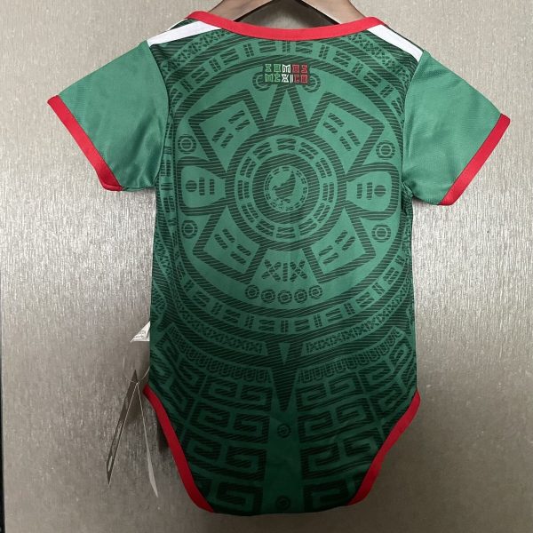 Green t-shirt on hanger, red trim at neck and sleeves, showing an intricate geometric pattern on the back.