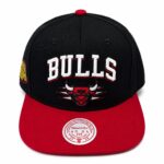 Black Chicago Bulls baseball cap with a red brim and bold white 'BULLS' embroidery on the front, featuring the team logo beneath.