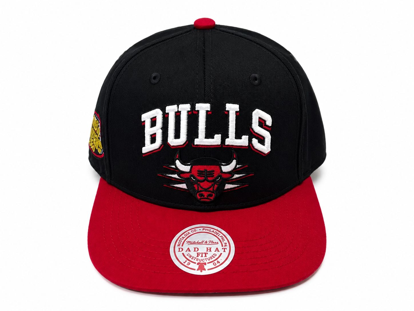 32466c30-f698-4059-b34d-15508ff35a9f | UAE SPORT STORE Black Chicago Bulls baseball cap with a red brim and bold white 'BULLS' embroidery on the front, featuring the team logo beneath.