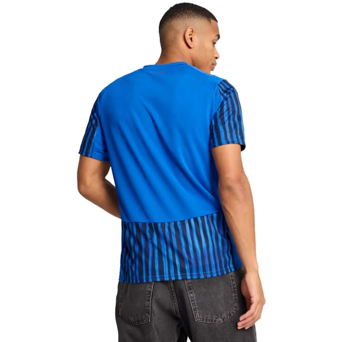 Back view of a man wearing a bright blue short-sleeve shirt with dark blue striped sleeves and striped hem, standing against a white background.