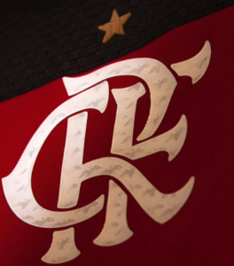 3333333_5778ca7a-84cb-4577-bbb8-3af546ba1845 | UAE SPORT STORE Close-up of a white stylized 'KC' monogram on red fabric, with a small gold star above it.