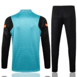 Turquoise goalkeeper jersey with black sleeves and orange armbands, paired with black athletic pants.