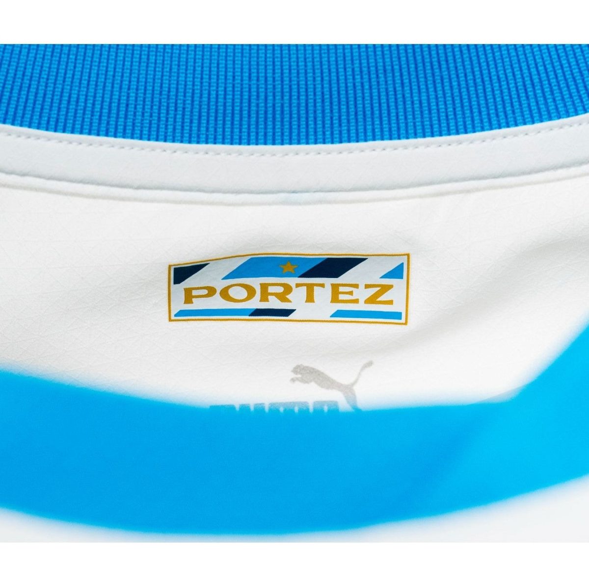 Close-up of a blue and white athletic shoe heel with a Portez logo on a white panel and a small Puma swoosh nearby