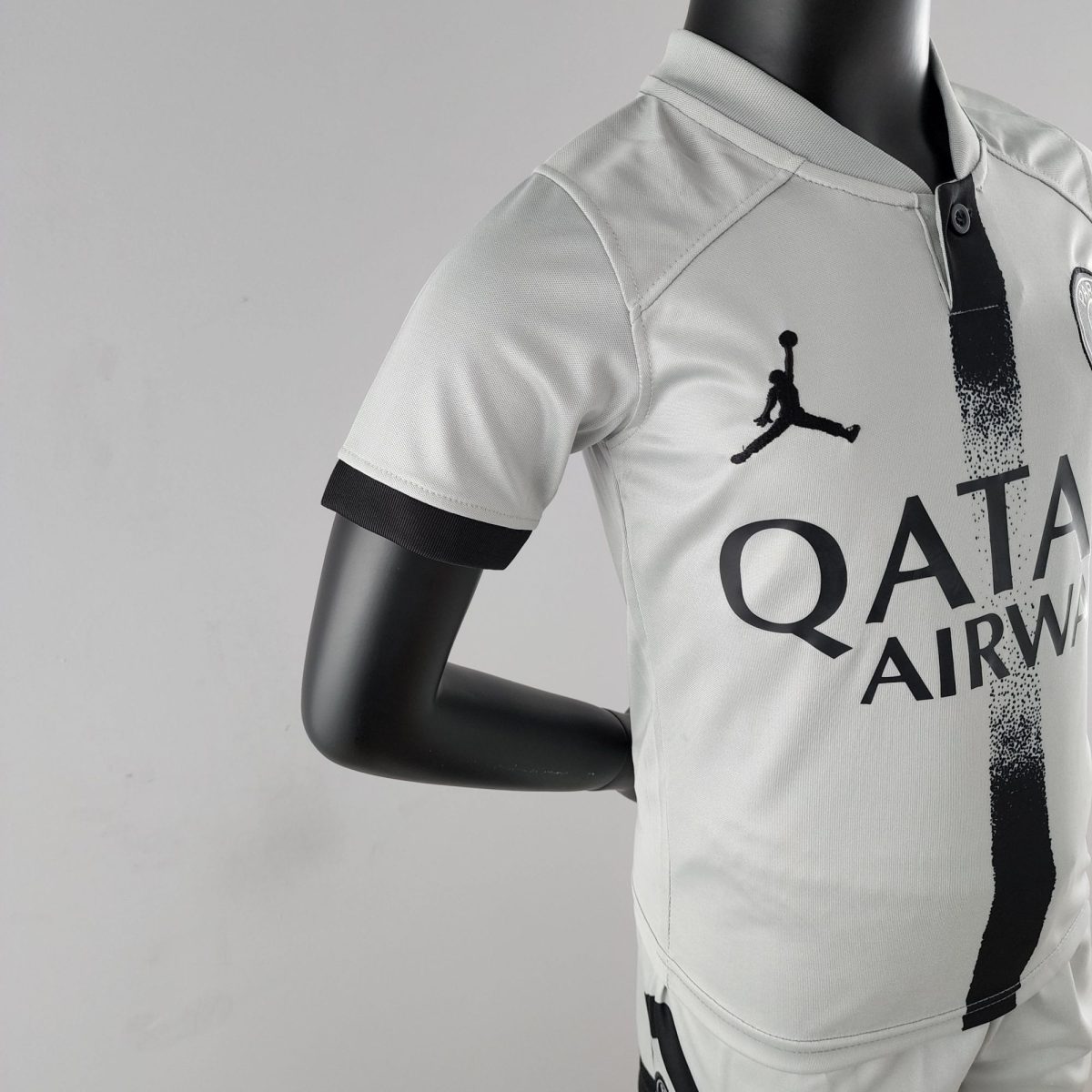 Close-up of a gray athletic shirt on a black mannequin, showing fabric texture and bold black graphic on the front near the chest area.