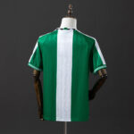 Back view of a green soccer jersey with a white vertical center stripe, displayed on a dress form mannequin.