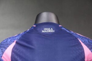 Back view of a dark blue and pink football jersey on a mannequin, with '¡Hala Madrid!' on the collar.