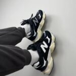 Casual black and white chunky sneakers with white socks resting against a light wall.