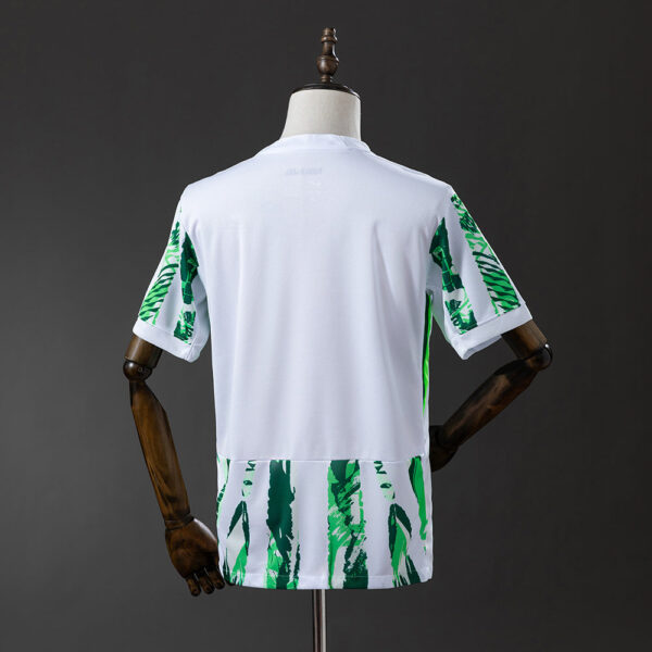 Back view of a white athletic jersey with green tropical leaf print on the sleeves and hem, shown on a mannequin's torso.