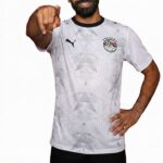 Man in a white geometric-patterned soccer jersey points at the camera, showcasing the Puma logo and club crest.