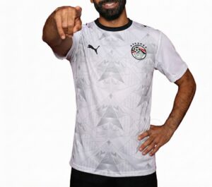 351b3bf7-1f11-42b8-86de-5561215141a2 | UAE SPORT STORE Man in a white geometric-patterned soccer jersey points at the camera, showcasing the Puma logo and club crest.