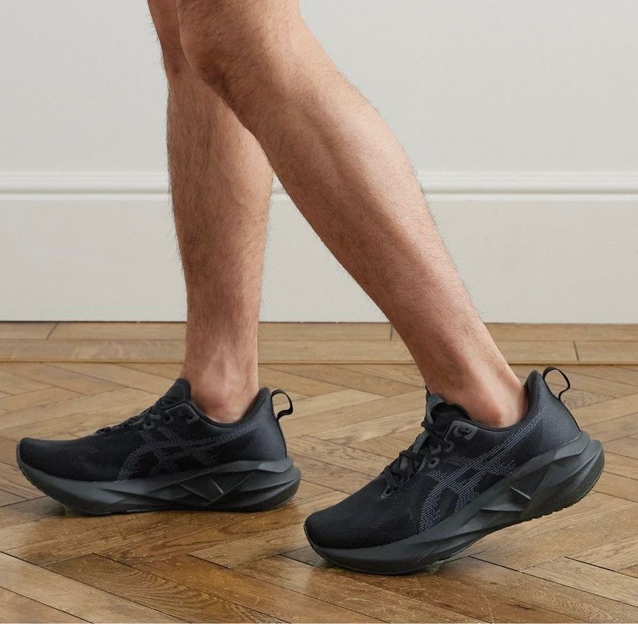 352a6765-6f42-46d8-a537-77a7475d9ec2 | UAE SPORT STORE Person wearing black athletic sneakers stepping forward on a wooden floor indoors.