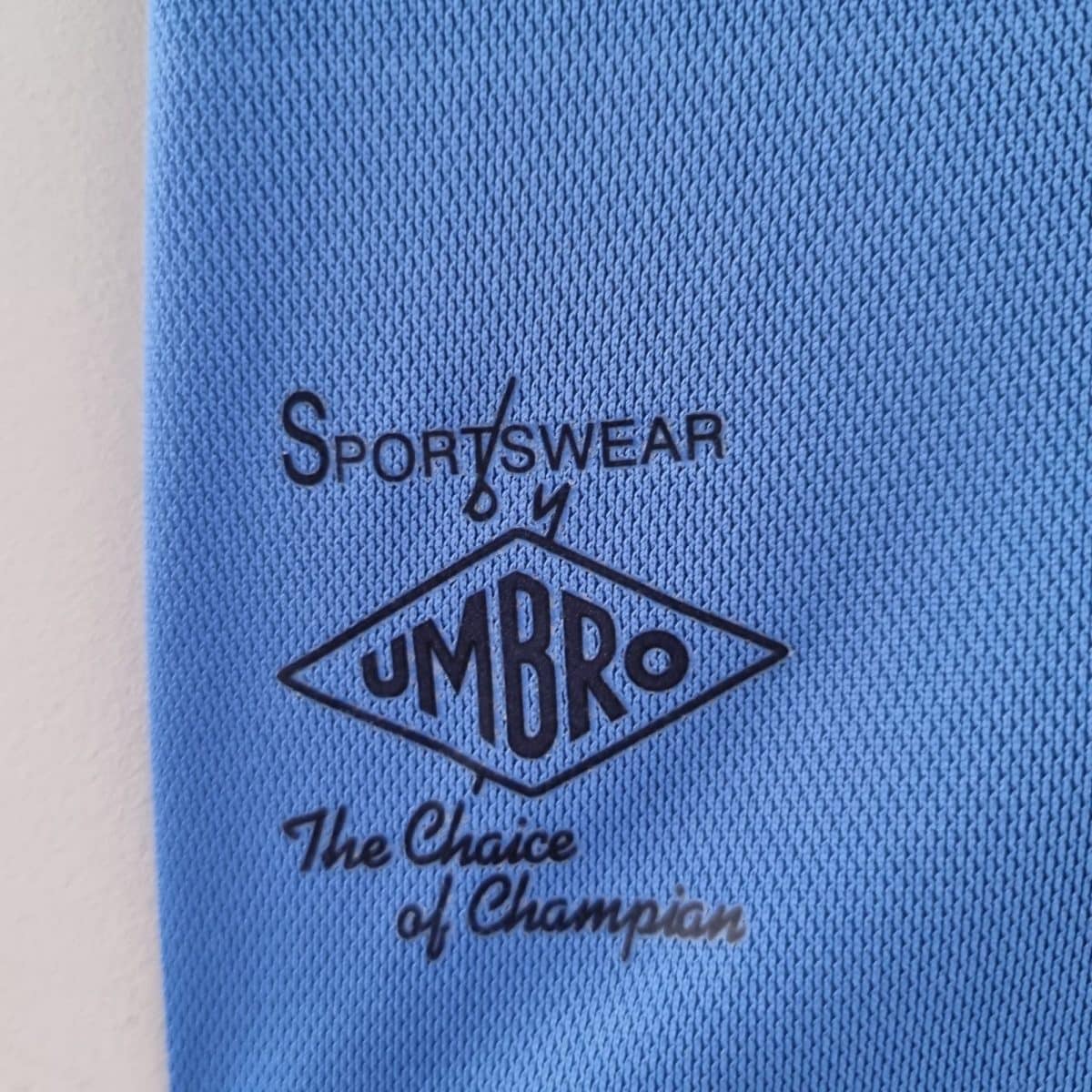 Close-up of blue fabric showing a black Umbro sportswear stamp and the word 'Sportswear'