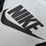 Close-up of a white fabric showing part of a bold black graphic or logo design on a clothing item.