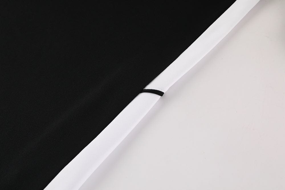 35b9c70a | UAE SPORT STORE Close-up of black fabric meeting a white border along a diagonal seam, with a small black thread loop.