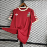 Red Adidas short-sleeve football jersey on a hanger, white collar and sleeve trim, with a crest on the left chest and Adidas trefoil on the right chest area.