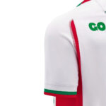 Close-up of a white sports jersey sleeve with red side stripe and green cuff trim, plus a partial green word 'GO' visible on the back shoulder area.