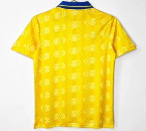 Back view of a bright yellow sports jersey with a blue striped collar and a white geometric pattern on the fabric, hanging on a hanger.