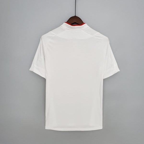 White shirt on a wooden hanger against a gray wall, back view showing a red inner collar lining