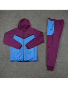 Purple and blue Nike tracksuit laid flat on gray carpet, hoodie jacket with zipper and matching joggers.