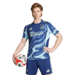 Soccer player in a blue uniform posing with a soccer ball against a green background.