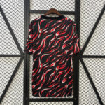 Black dress with red and white wavy pattern on a wooden hanger, against a metal mesh wall.