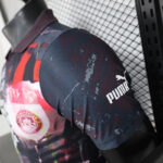 Close-up of a Manchester United jersey sleeve with the PUMA logo on dark, maroon patterned fabric.