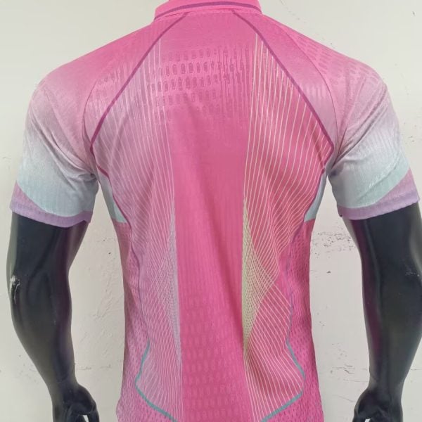 Back view of a bright pink cycling jersey on a mannequin, featuring diagonal white lines and teal trim along the hem and sleeves.